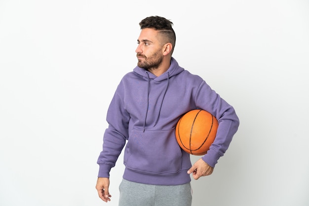 Foto uomo del giocatore di pallacanestro isolato su priorità bassa bianca che osserva al lato