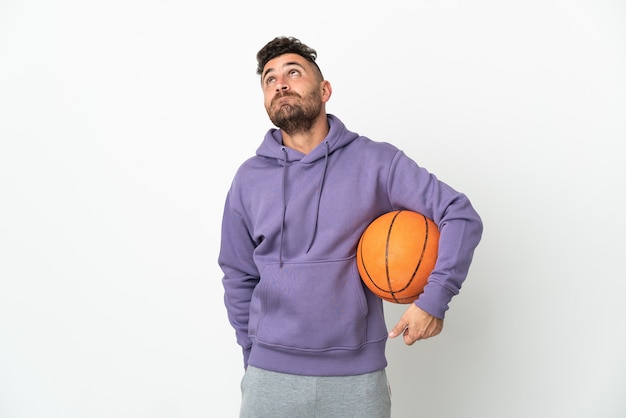 Basketball player man isolated on white wall and looking up