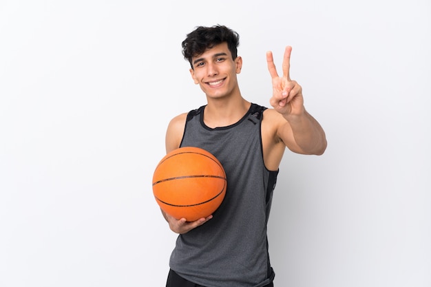 Basketball player man over isolated white wall smiling and showing victory sign