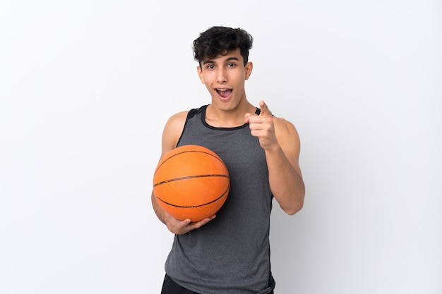 Basketball player man over isolated white wall surprised and pointing front