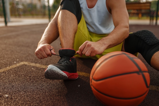 Фото Баскетболист, завязывающий шнурки на открытом корте