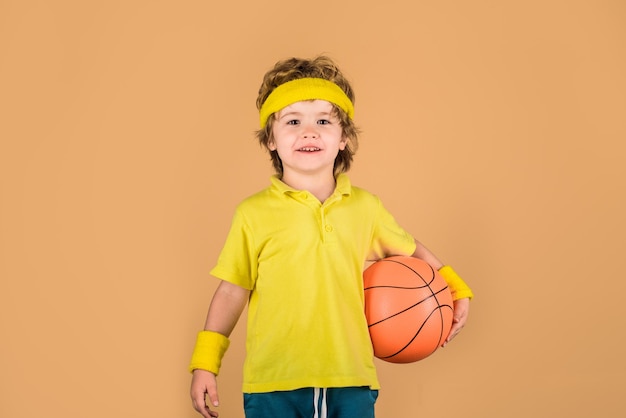 ボールを持つバスケットボール選手かわいい男の子は、バスケットボールを少し遊んでいるバスケットボールの愛らしい子供を保持しています