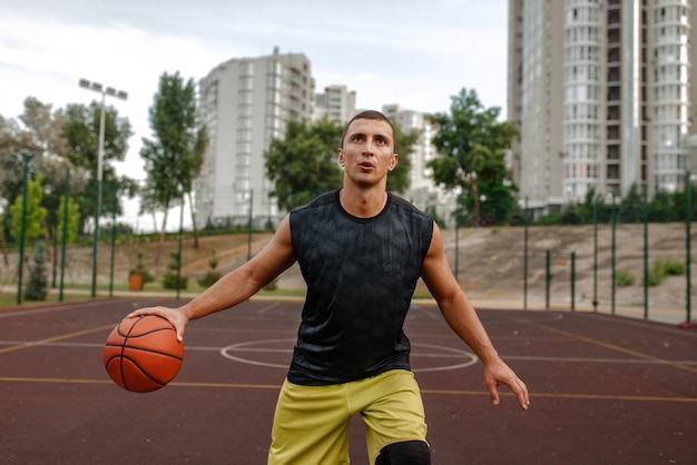 Basketball player with ball in motion on outdoor court.