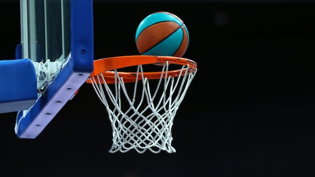 Basketball ring with a net in which the ball flies on a dark\
background