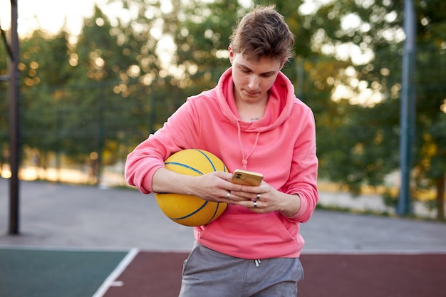 Foto basketballer tienerjongen chatten met vriend terwijl hij wat vrije tijd heeft na de wedstrijd