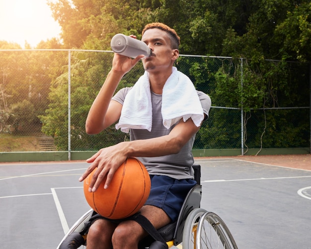 Foto basketbalspeler drinkwater of man in rolstoel voor sportpauze rust of fitness elektrolyten op de baan persoon met een handicap atleet of fles voor hersteloefening en training wellness