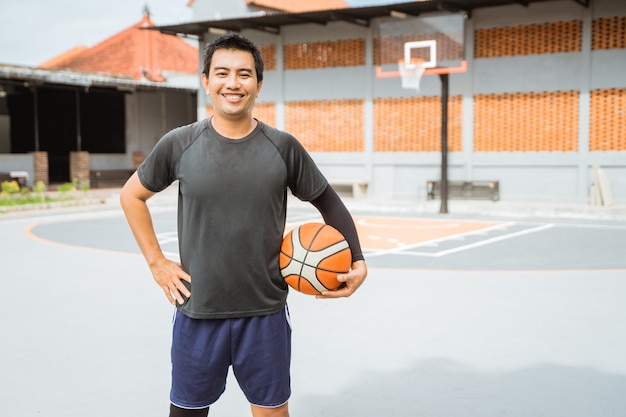 Basketbalspeler lacht terwijl hij een basketbal vasthoudt met zijn handen