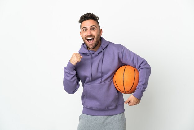 Basketbalspeler man geïsoleerd op een witte achtergrond vieren een overwinning in winnaar positie