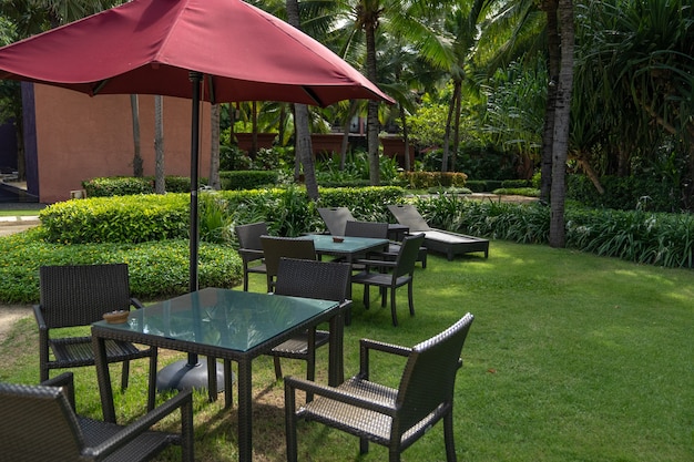 The basketry chair, table and red umbrella set in the garden, in the relax area.