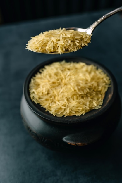 Basmati rice groats in a clay pot on a dark background