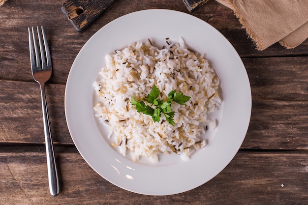 Basmati rice with herbs on a white plate on a wooden table