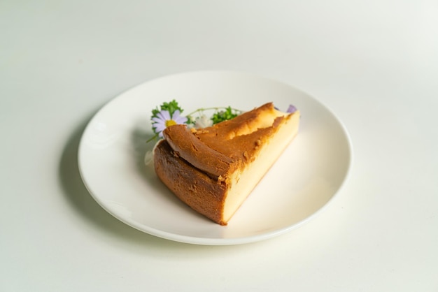 하얀 접시에 꽃을 넣은 바스크 번트 치즈케이크 데코라토인