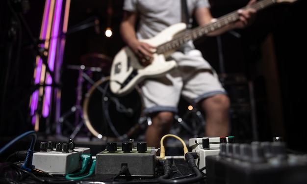 Bass guitar player on a stage with set of distortion effect pedals.