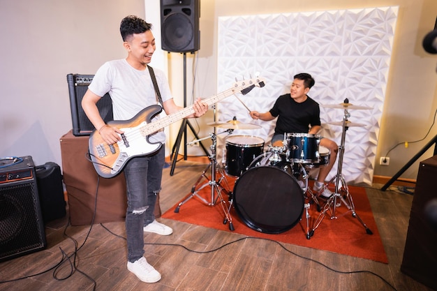 A bassist and a drummer enjoying a band with background speakers