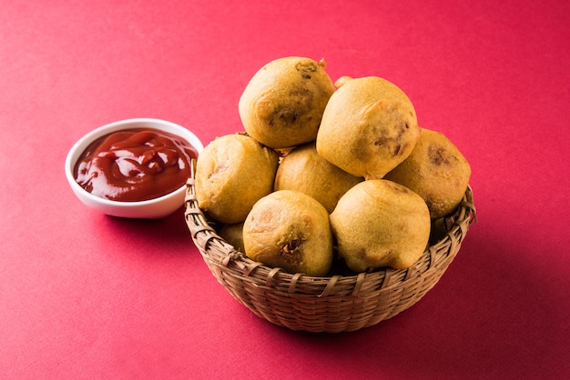 Batata Vada or Aloo Bonda is a tasty and popular indian tea-time snack served with green chillies and tomato ketchup. Selective focus