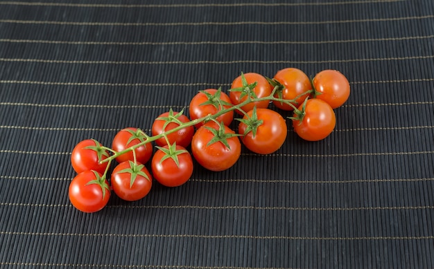 Batch of baby tomatoes on black bamboo background