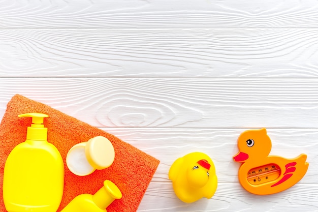 Bath accessories for kids Yellow rubber duck towel cream shampoo on white wooden