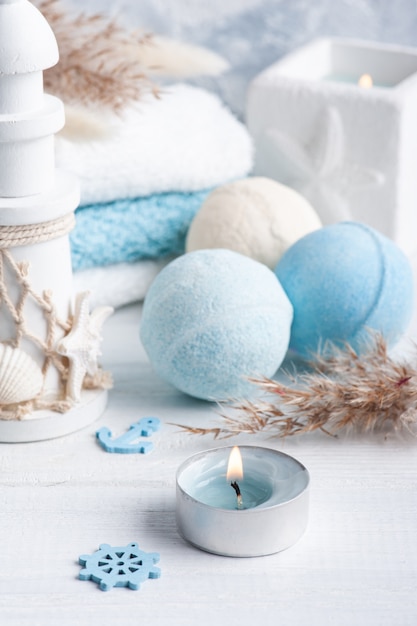 Bath bombs with dry flowers, lit aroma candles and towels