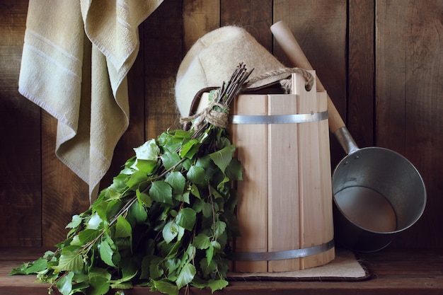 Bath broom made of birch and wooden bucket in a Russian bath