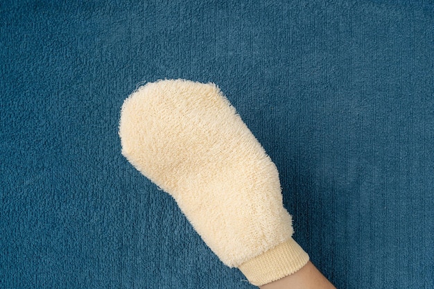 スパマッサージ用のナチュラルベージュの洗 ⁇ 手袋 健康的な肌の剥離 シャワー手袋 ブルーテリータオル背景