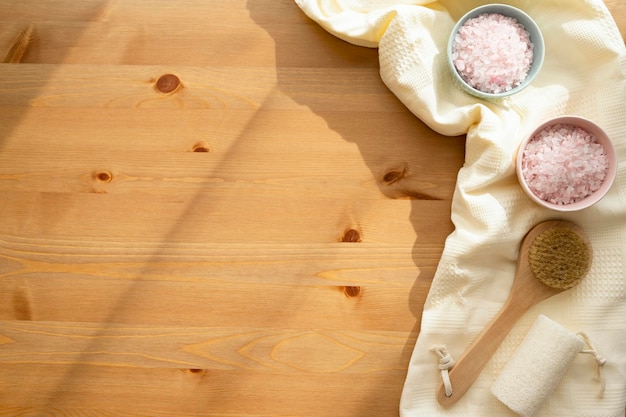 Bath salt in bowl on wooden background top view