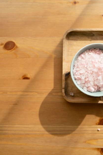 Bath salt in bowl on wooden background top view