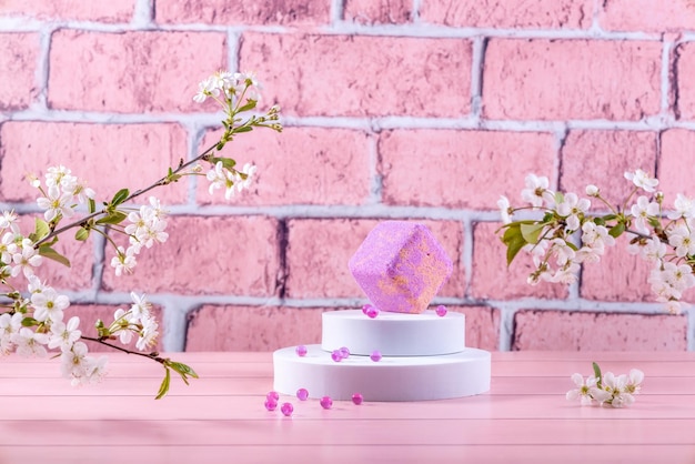 Bath salts and aromatic bath balls on a white round podium and cherry blossoms