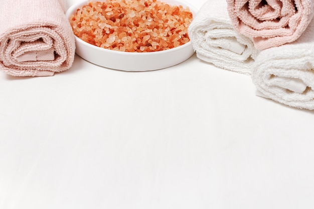 Bath towels and aroma sea salt on concrete white background. Spa theme. Copy space.