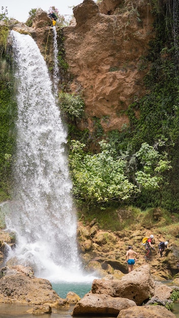 Bathers under a large waterfall