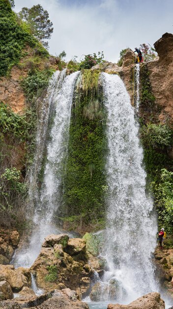 Bathers under a large waterfall