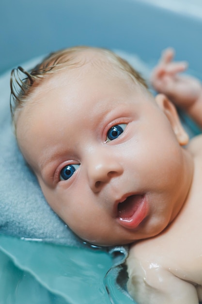 Bathing a baby in a baby bath The first bath of a newborn baby A baby bathes in a bath with water Personal hygiene of a newborn