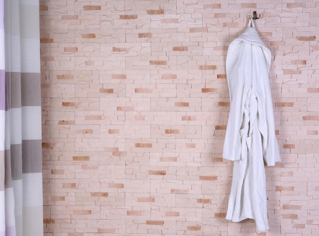 Foto abito da bagno appeso al muro di mattoni