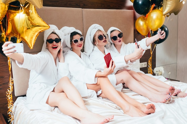 Bathrobe party girls taking selfie. Females leisure and lifestyle. Sunglasses and towel turbans on
