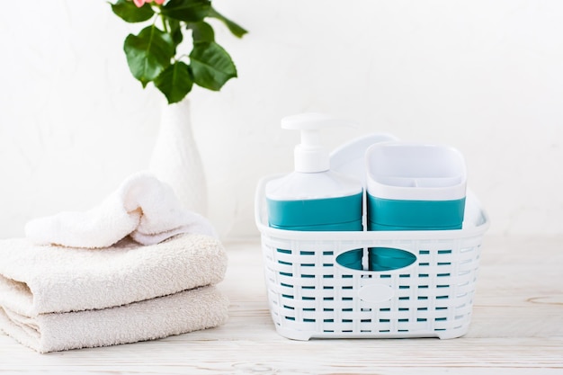 Bathroom accessories in a basket and a stack of towels on the table Organization and order