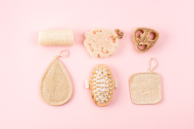 Foto accessori da bagno, spugna di luffa naturale, spazzola di legno su sfondo rosa