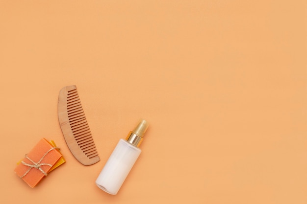 Bathroom accessories with zero waste bars of solid soap, cosmetic spray bottle, wooden comb on a beige background