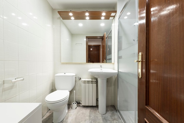 Bathroom in cream and brown tones with dark wood cabinet and square mirror next to the shower