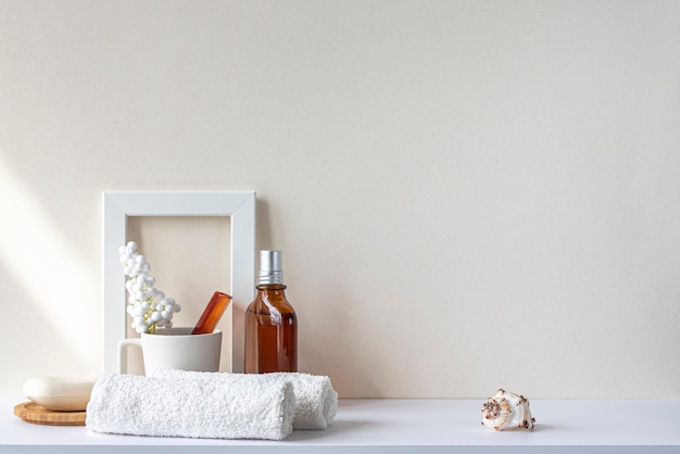 Photo bathroom interior in beige pastel tone. white shelf in bathroom with towels, soap, perfume bottle, hairbrush, houseplant. mockup with space for text. minimal composition.