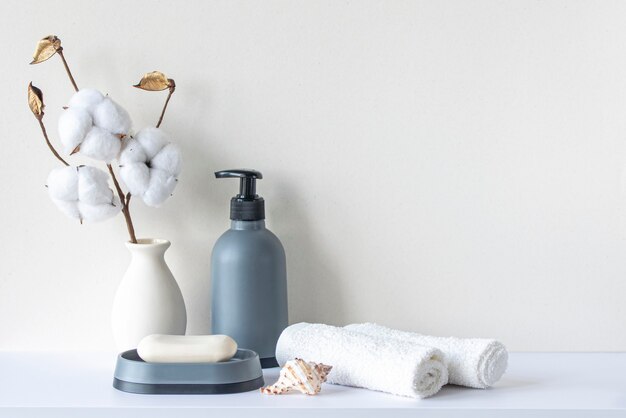 Foto interno del bagno in tono beige pastello ripiano bianco in bagno con asciugamani sapone shampoo bottiglia towels