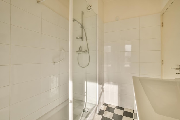 Interno del bagno nei toni del bianco e piastrelle sul pavimento a forma di scacchi con doccia e lavabo