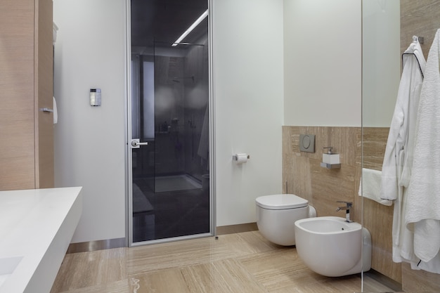 Bathroom interior with wallhung toilet and bidet and walkin shower