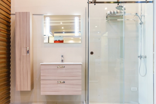 bathroom interior with white walls, a shower cabin with glass wall, a toilet and sink