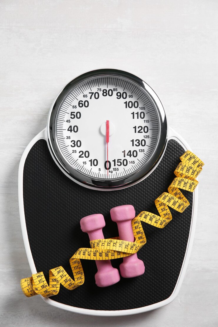 Photo bathroom scale measuring tape and dumbbells on white wooden background flat lay