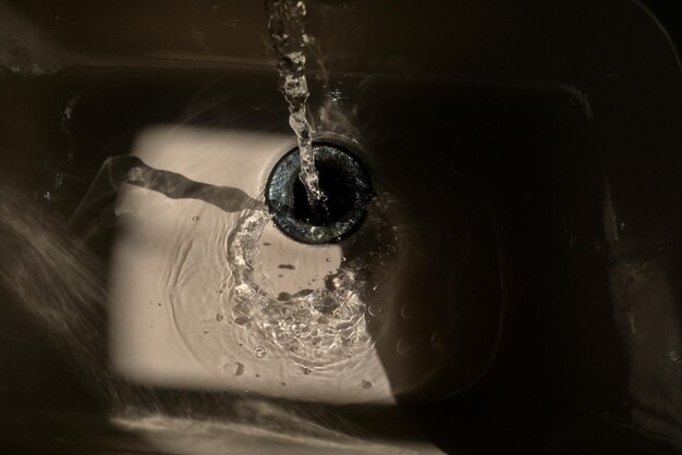 Foto il lavandino del bagno bagnato dall'acqua del rubinetto riflessi e gocce d'acqua a bassa luce