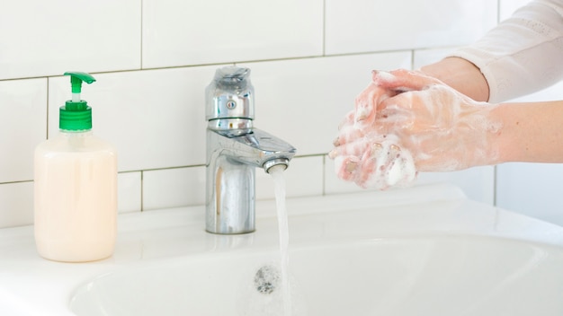 Bathroom sink with liquid soap and washing hands