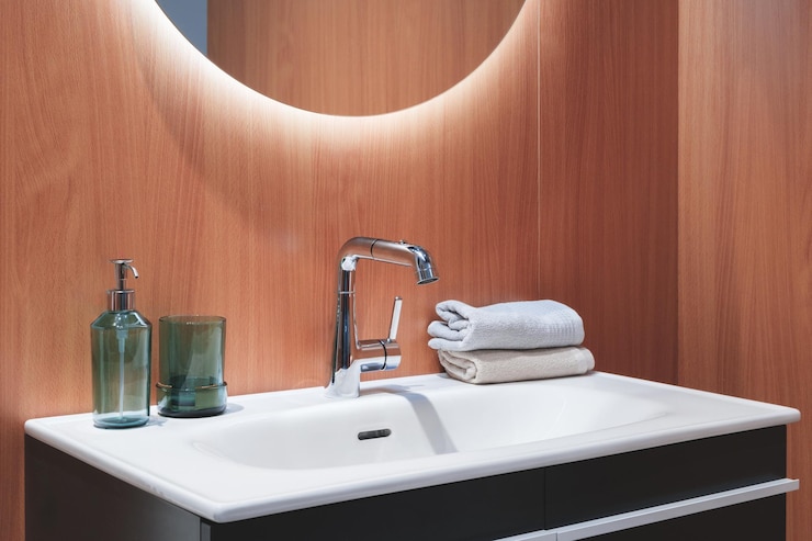 Photo a bathroom sink with a silver faucet and a white basin a green bottle and a green vase are on the counter a white towel is folded and placed on the counter