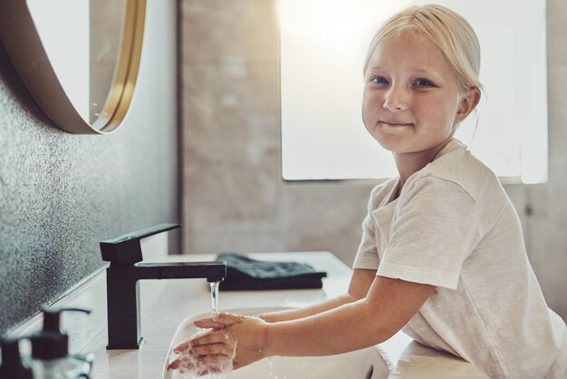 Photo bathroom water and portrait of child washing hands with soap foam and healthy hygiene cleaning dirt germs and bacteria on fingers happy girl in home for morning wellness safety and skin care