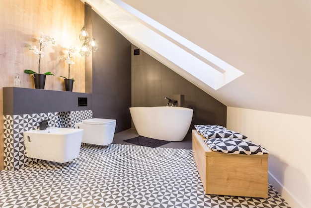 A bathroom with a bathtub and a white tub with black tiles.