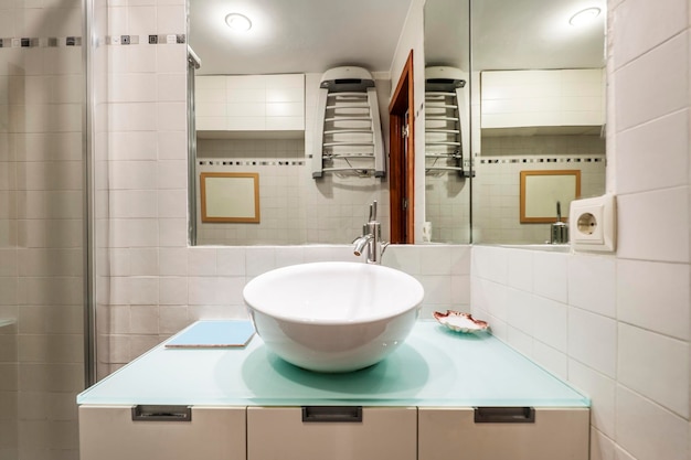 Bathroom with concave white porcelain sink glass top and white lacquered furniture