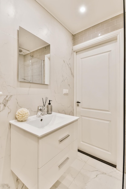 Photo a bathroom with marble flooring and white walls along with a large mirror on the wall above the sink